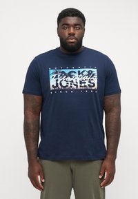 Mørkeblå kortærmet t-shirt lavet af bomuld, med et grafisk print af palmer og byens skyline, standard pasform med rund hals.