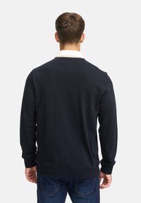 Marineblå hettegenser med lange ermer, rund halslinning og ribbestrikkede mansjetter og kant. Laget av myk stoff, designet for en avslappet passform.