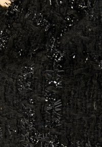 Tessuto nero testurizzato con un motivo intrecciato e paillettes nere lucide mescolate, creando un effetto visivo stratificato e una superficie variata.