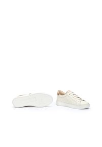 Zapatillas de cuero blanco con diseño perforado, detalles en el talón en tono marrón y suelas de goma planas, que presentan cordones y detalles de marca mínimos.