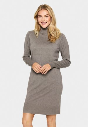 Knit turtleneck dress in light brown, with long sleeves and ribbed cuffs. Smooth texture, knee-length, featuring a fitted silhouette.