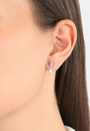Pendientes de plata que presentan una gema rectangular transparente y una pequeña perla, con un diseño moderno. Superficie lisa y acabado pulido.
