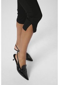 Black leather slingback heels with pointed toes and a decorative strap across the front. Shiny finish and slim stiletto heel. Lightweight.