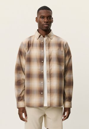 Brun og beige ternet skjorte med knapper, krave, enkelt brystlomme og glat tekstur, lagdelt over en hvid t-shirt.