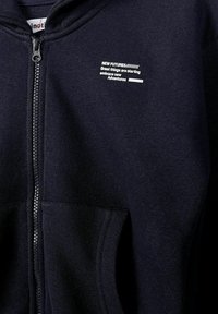 Sweat à capuche zippé bleu marine avec texte blanc sur la poitrine : "NEW FUTURES De grandes choses commencent, embrassez de nouvelles aventures."