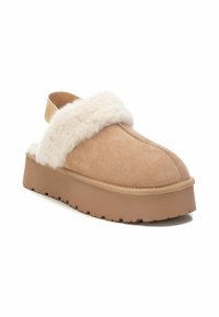 Zoccoli in suede beige con una morbida fodera in pelliccia bianca, punta arrotondata e suola piatta spessa. Presentano uno stile slip-on con una fascia di supporto sul retro.
