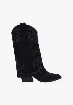Botas de vaquero de ante negro con punta afilada, adornadas con tachuelas plateadas en un patrón en espiral, tacón bajo y apilado, y una tira en la parte superior.