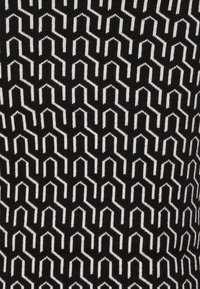 Svart tyg med ett geometriskt vitt mönster av zigzagformer, med vertikala linjer och framträdande toppar i en repetitiv design.