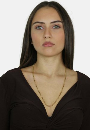 Collana d'oro indossata sopra una maglietta marrone. La collana presenta piccoli anelli rotondi e pende liberamente attorno al collo.