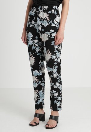 Black floral pants with a floral pattern in light blue and beige, featuring a relaxed fit and elastic waistband. Worn with black block-heeled sandals.