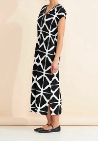 Svart och vit ärmlös klänning med V-ringning, med ett geometriskt mönster och sidoklipp. Matchad med svarta platta skor.