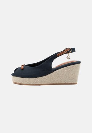 Marineblauwe sleehak sandaal met peep toe, gestructureerde beige platformzool, verstelbare enkelband met gouden gesp en klein hangend hangertje.