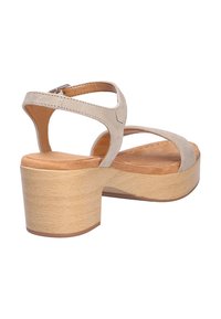 Beige Wildledersandale mit Kreuzriemen-Design, verstellbarem Knöchelverschluss und Blockabsatz. Die natürliche Holzmaserung auf dem Absatz sorgt für zusätzliche Details.