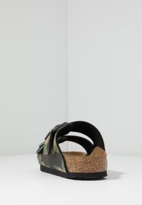 Infradito con motivo mimetico, dotate di due cinturini regolabili, soletta in sughero e suola nera. Design con apertura sul retro per una facile calzata.