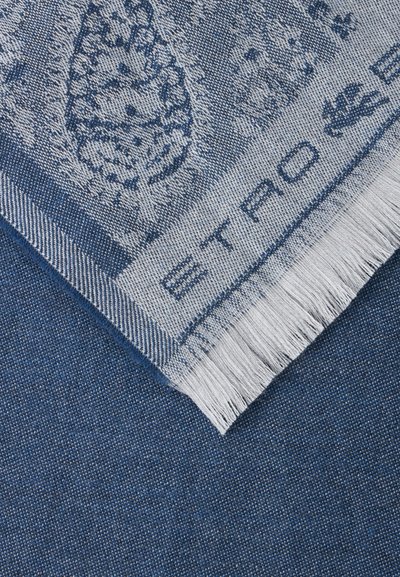 Coin de tissu tissé bleu et blanc avec des franges, présentant des motifs complexes et le texte "ETRO" le long du bord.