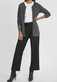 Gray textured cardigan with a round neckline, worn over a white t-shirt. Paired with black wide-leg pants and dark heeled boots.