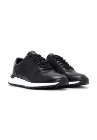 Sneaker in pelle nera con dettagli perforati, lacci neri piatti, suola in gomma bianca e punta arrotondata. Finitura liscia con accenti sottili.