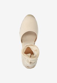 Beige espadrille met een canvas bovenkant, ronde neus en enkelband. Heeft een geweven textuur bij de hiel en een jute touw zool.
