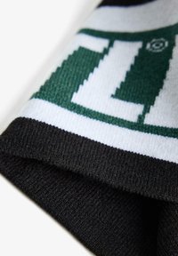Knitted scarf featuring a mix of green, white, and black colors, with a geometric pattern and ribbed texture along the edges.