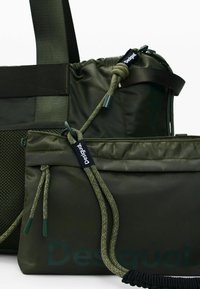 Grønne nylonposer med tekstureret net og snøre lukninger. Indeholder låseklemmer og et logomærke. Forskellige størrelser stablet sammen.