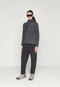 Hallid hall fliisjakker kõrge kaelusega ja lukuga taskutega, kaasas mustad püksid, millel on lukuga aksent. Kanda hallide kingadega.