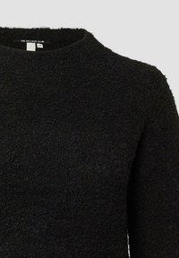 Czarny sweter z teksturowanej, puszystej tkaniny. Posiada okrągły dekolt i długie rękawy. Etykieta widoczna przy kołnierzyku z nazwą marki i rozmiarem.