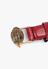 Rode leren riem met een messing gesp met verenpatroon, versierd met sprankelende accenten en een zwart edelsteen oogdetail.