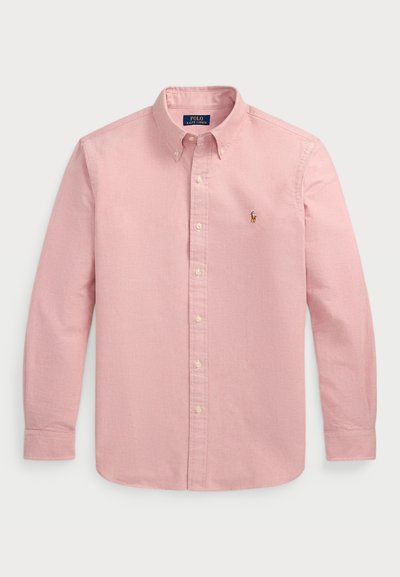 Heledad roosa, pika varrukaga kaelusega särk nööbiga esiosas, millel on kangatekstuur ja väike tikand logoga vasakul rinnal.