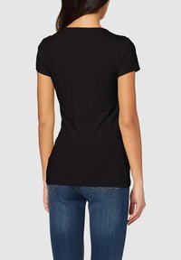 T-shirt nero a maniche corte, realizzato in tessuto morbido, aderente in vita, con scollatura rotonda e dettagli di cucitura minimal lungo l'orlo.