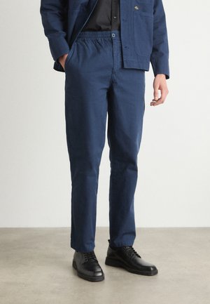 Navy blue elastic-waist pants made of sturdy fabric, featuring a straight-leg cut and side pockets, paired with black leather shoes.