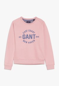 Różowa bluza z miękkiego materiału, z okrągłym dekoltem i rękawami raglanowymi. Na bluzie znajduje się nadrukowany tekst "East Coast GANT" w kolorze niebieskim.