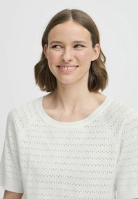 Gebreide witte sweater met een ronde hals, korte mouwen en een textuurpatroon met kleine perforaties door het gehele kledingstuk.