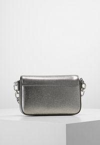 Borsa a tracolla metallica argentata con superficie testurizzata, dotata di una tasca frontale e di una tracolla a catena removibile. Forma rettangolare con un design elegante.