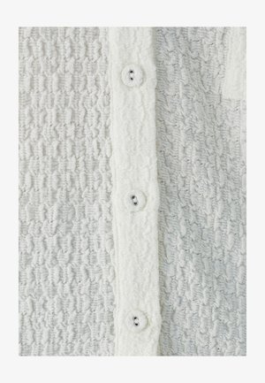 Textured white fabric with a crinkled pattern; five buttons at the front; soft and fluffy texture; buttonholes visible on the button placket.