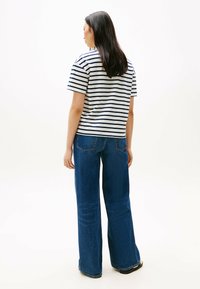 Camiseta de rayas de manga corta en gris y azul marino, combinada con unos vaqueros oscuros de tiro alto y corte holgado. Ajuste simple y relajado, con pierna recta.