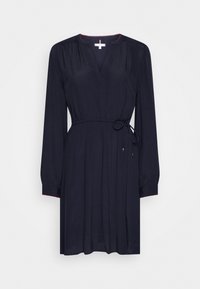 Mörkblå klänning med lång ärm, V-ringning och justerbart midjeband, med röda accenttrådar längs ringningen och ärmarna.