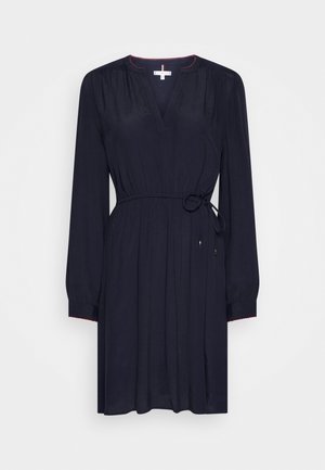 Marineblaues Kleid mit langen Ärmeln, V-Ausschnitt und verstellbarem Taillengürtel, versehen mit roten Akzentnähten entlang des Ausschnitts und der Ärmel.