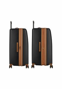 Valise noire avec des accents bruns, coque rigide, forme rectangulaire, poignée rétractable et quatre roues pour la mobilité. Fermeture zippée visible.