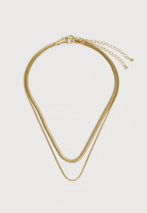 Kétsoros aranyszínű lánc nyaklánc állítható kapoccsal és hosszabbító láncokkal, egyszerű világos háttéren.