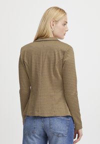 Brun rutigt blazer med skräddarsydd passform, enkelknäppt design, slagkrage och långa ärmar; textil med subtil mönstring.