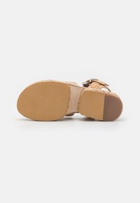 Ljusbruna kvinnors sandaler med flätade läderremmar, vadderad sula och en slät gummisula med en lätt klack.