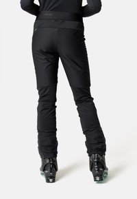 Pantalons de ski noirs avec une coupe ajustée, fabriqués en matériau doux et flexible, dotés d'une taille haute et de jambes inférieures renforcées.