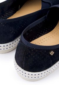 Marineblauwe suède ballerina's met geperforeerd ontwerp, elastische rand en lichtgekleurde gevlochten zool. Bevat een klein metalen logo-detail aan de zijkant.