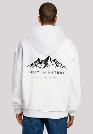 Weißer Hoodie mit einem schwarzen Berggrafik und dem Text "VERLOREN IN DER NATUR" über "gefunden in den Bergen" auf dem Rücken. Verfügt über eine große Kapuze.