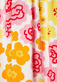 Tissu plissé avec de grands motifs floraux colorés en orange, rose, rouge et jaune sur fond blanc.