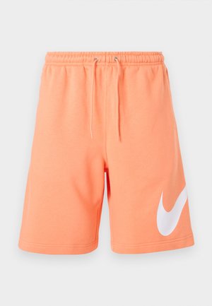 Perzikkleurige short met trekkoord, elastische tailleband en groot wit Nike Swoosh-logo op de linkerbroekspijp.
