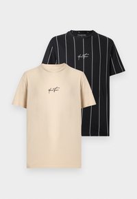 T-shirt beige uni et T-shirt noir avec des rayures blanches verticales, tous deux avec un petit logo en écriture cursive « Your Turn » centré sur la poitrine.