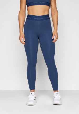 Leggings blu navy realizzati in materiale elasticizzato con una texture morbida, abbinati a un crop top coordinato con un cinturino con marchio.