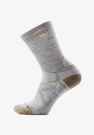 Chaussette grise montante avec texture côtelée, accents marron au talon et à l'orteil, et fines rayures orange près de la tige et du talon, présentée sur un modèle de pied.