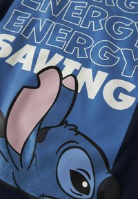 Niebieski materiał tekstylny z grafiką postaci o dużych uszach. Napis "ENERGY SAVING" w pogrubionych białych literach na niebieskim tle.